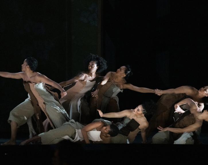 Six dancers perform on stage during the world premiere opera INTELLIGENCE, five leaning back while one reaches forward