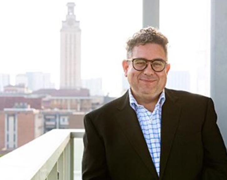 A headshot of Dean Ramón Rivera-Servera standing with the UT tower in the background