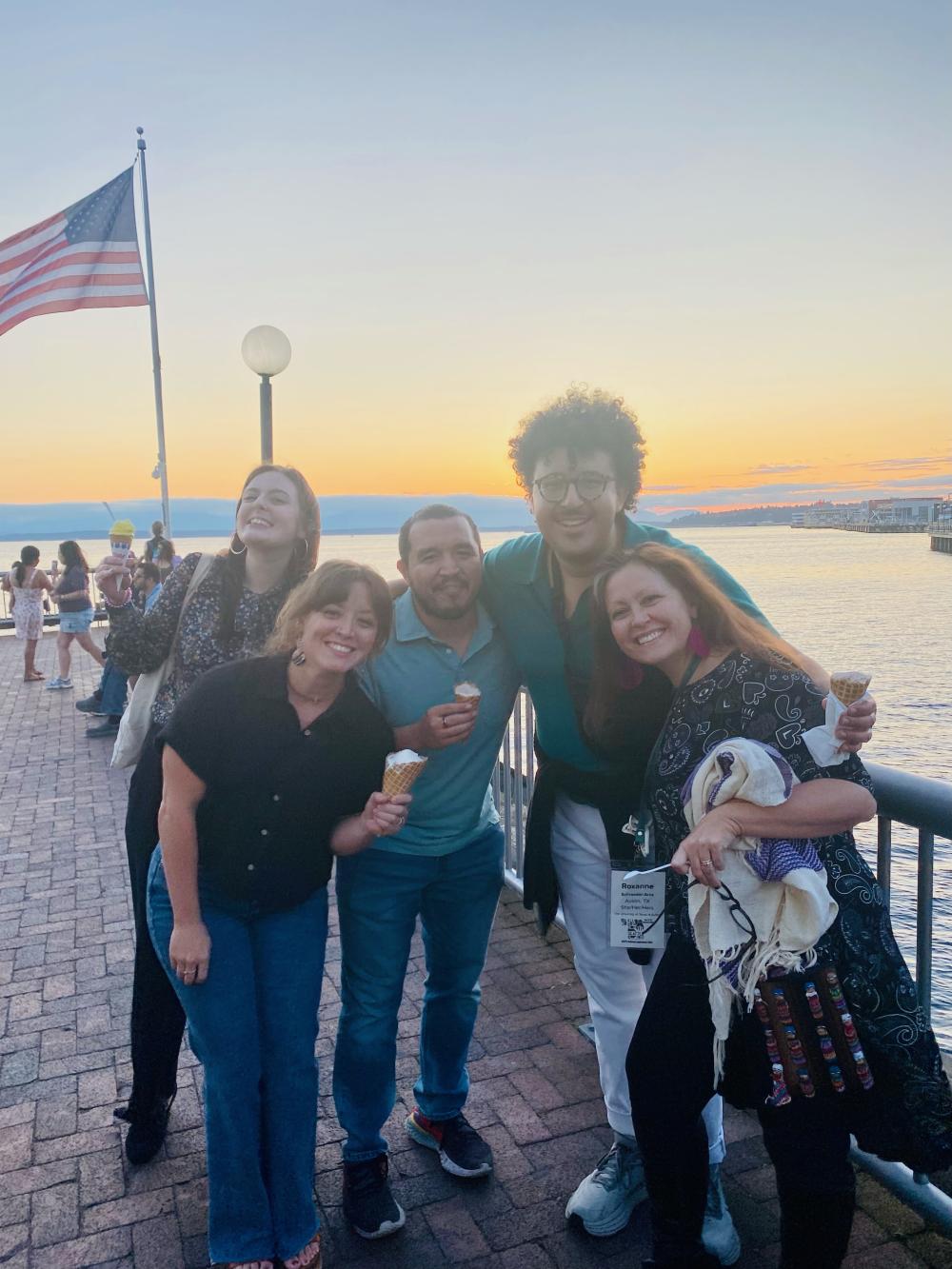 Faculty, students and alumni pose together with ice cream cones on a pier in Seattle