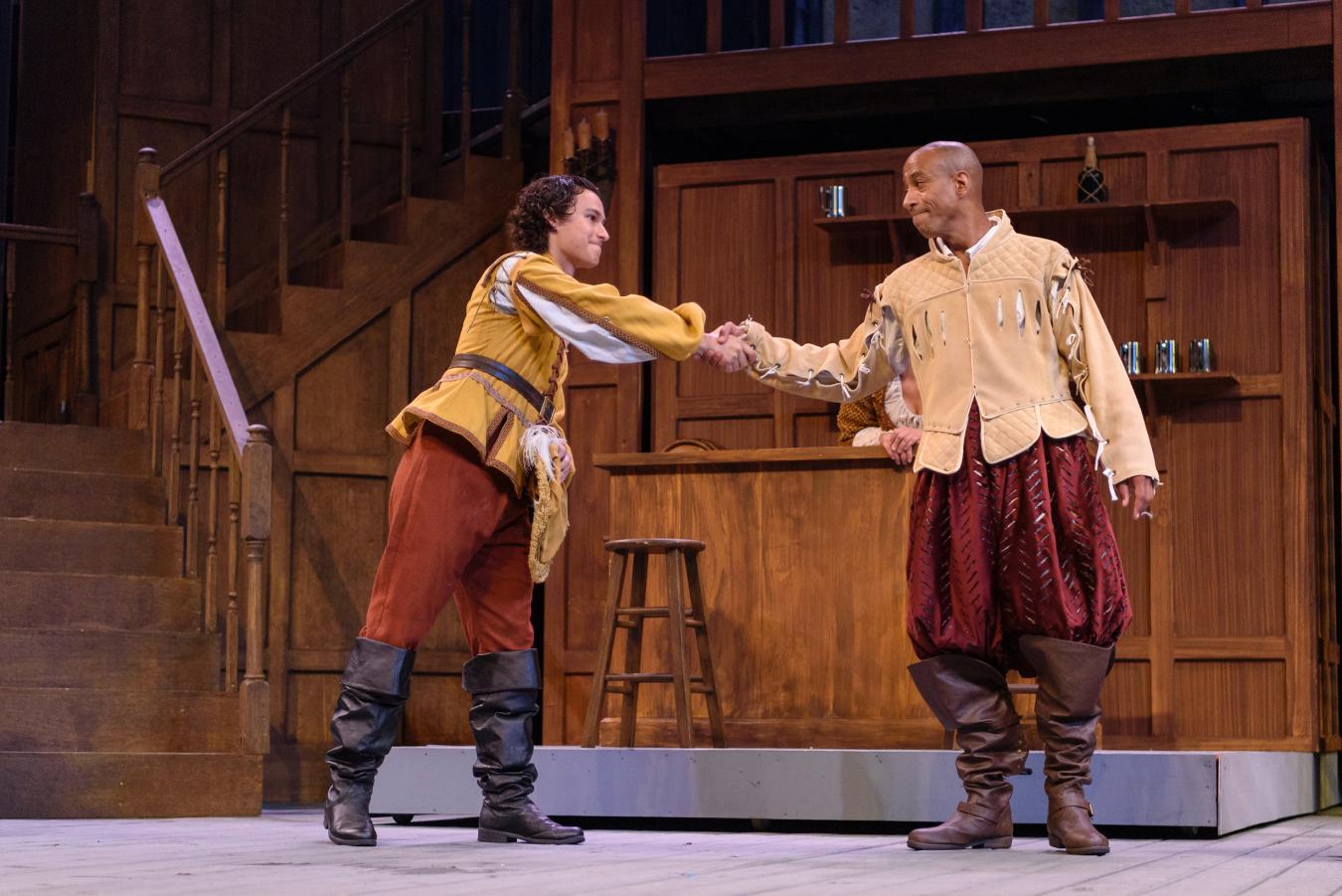 Actor and current student Dominic Gross performs on stage, shaking hands with another actor