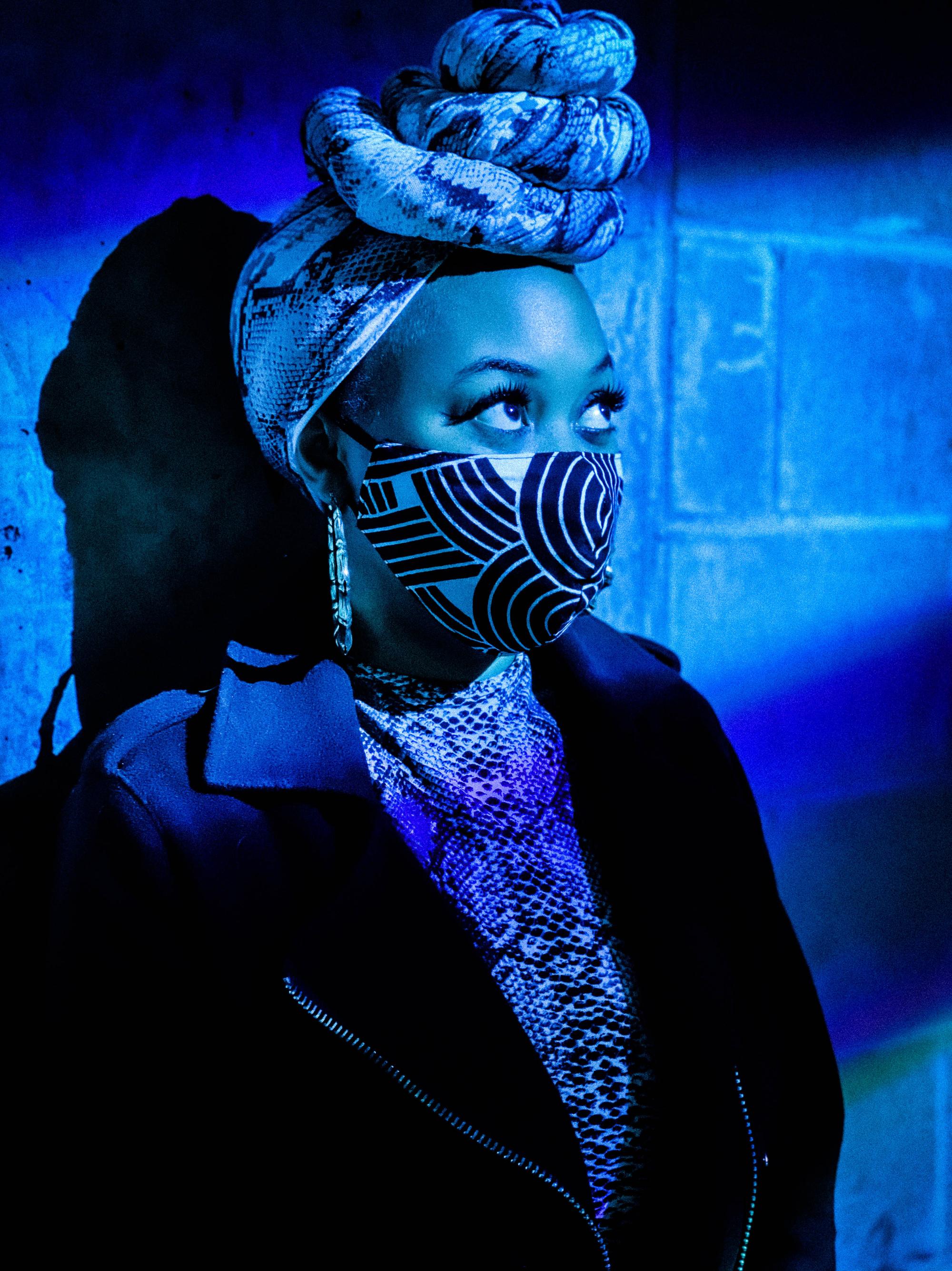 actress wearing a knotted wrap around her head and a mask washed in blue light