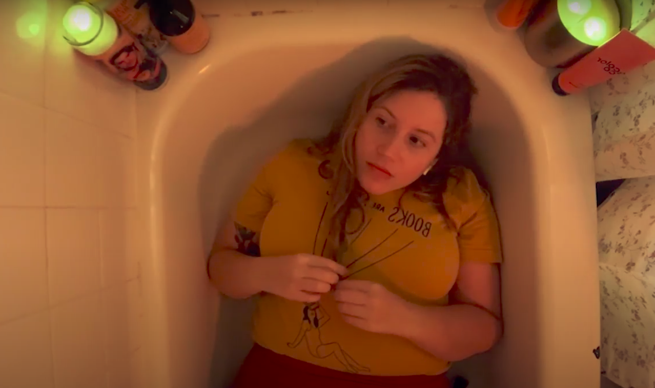 actress in a yellow shirt lies down in her bathtub