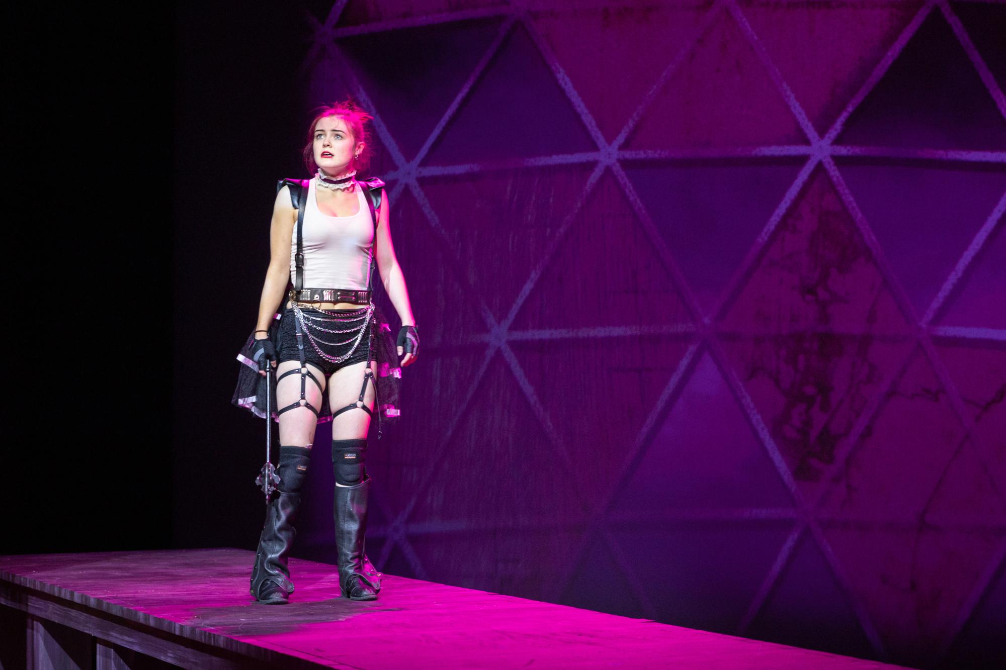 actor in a WWE maid costume looks concerned, with pink stage lighting