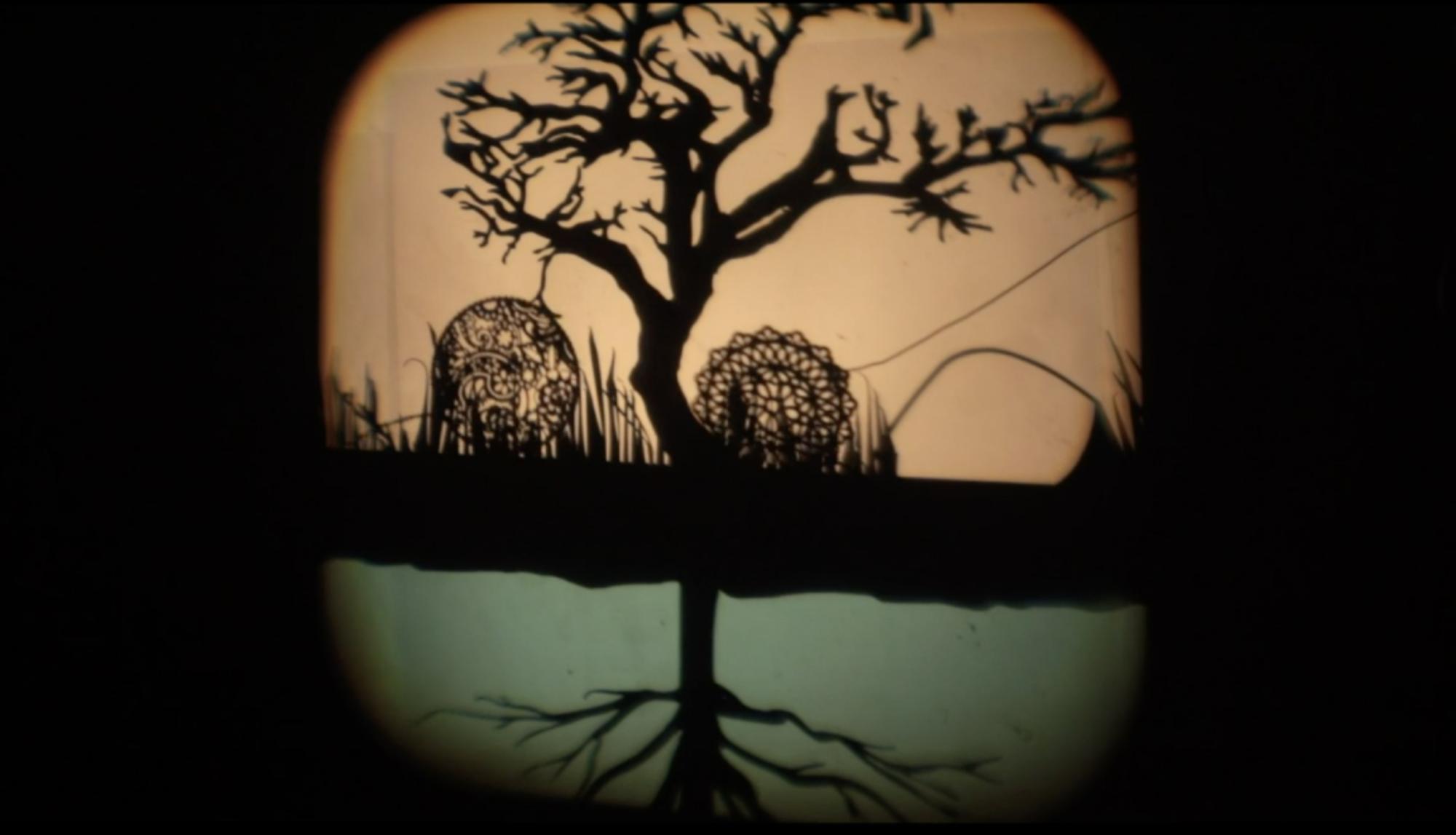 a projected shadow puppet display featuring a tree, its root system and two designed circles