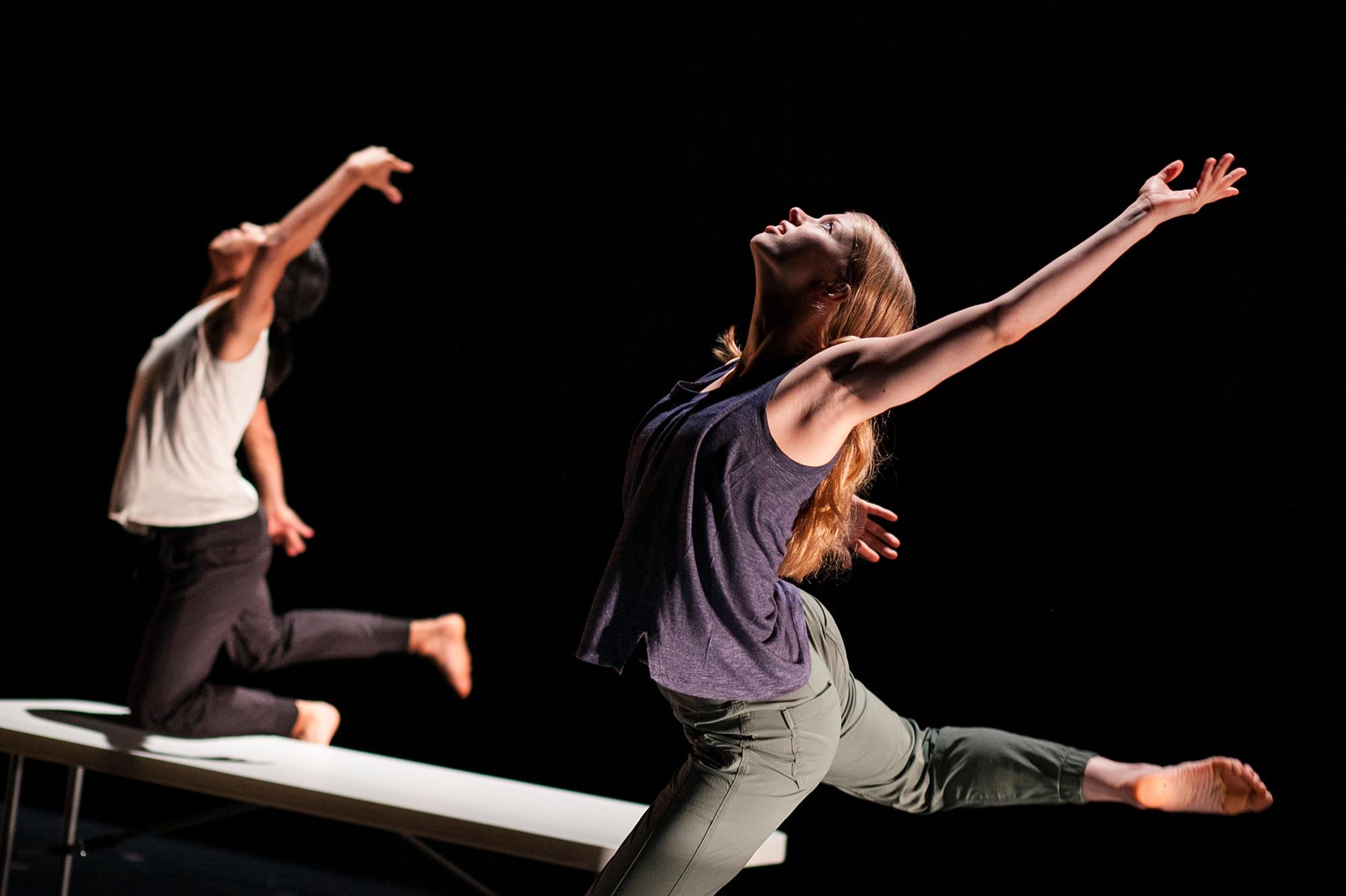 dancers kneeling on a table with arms raised