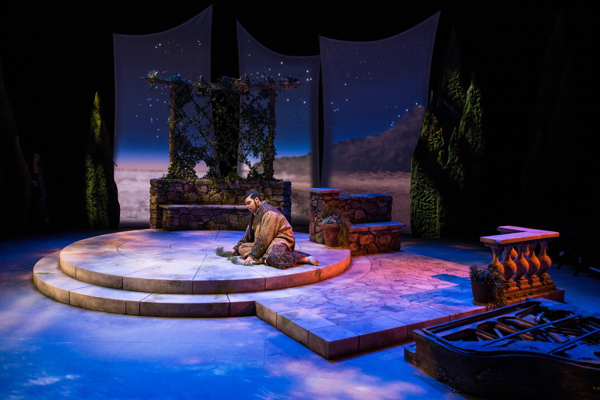 Twelfth Night production of a man seated on a center round platform