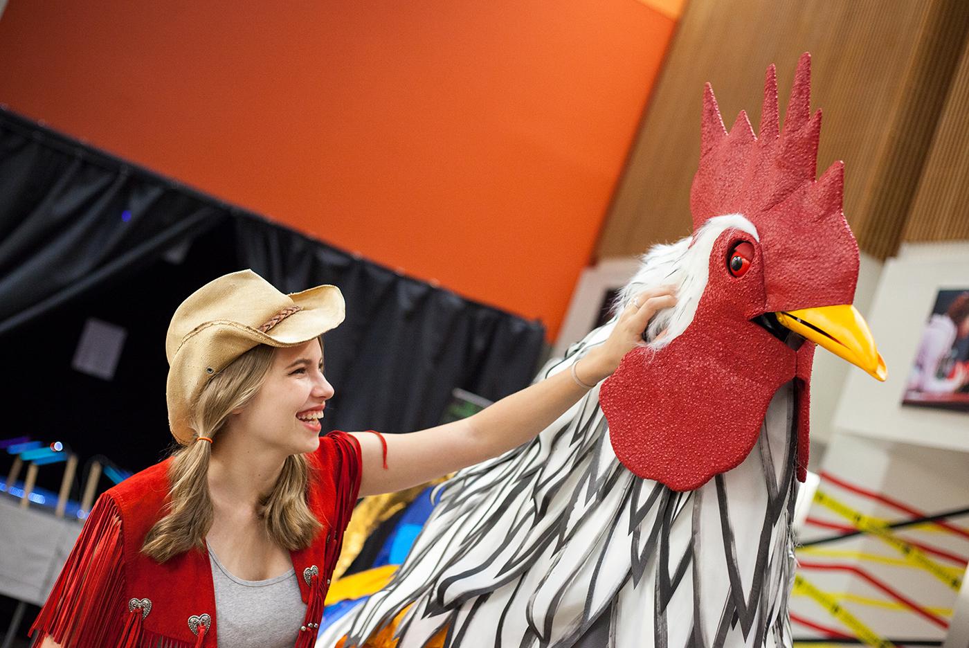 woman in cowboy hat petting giant chicken