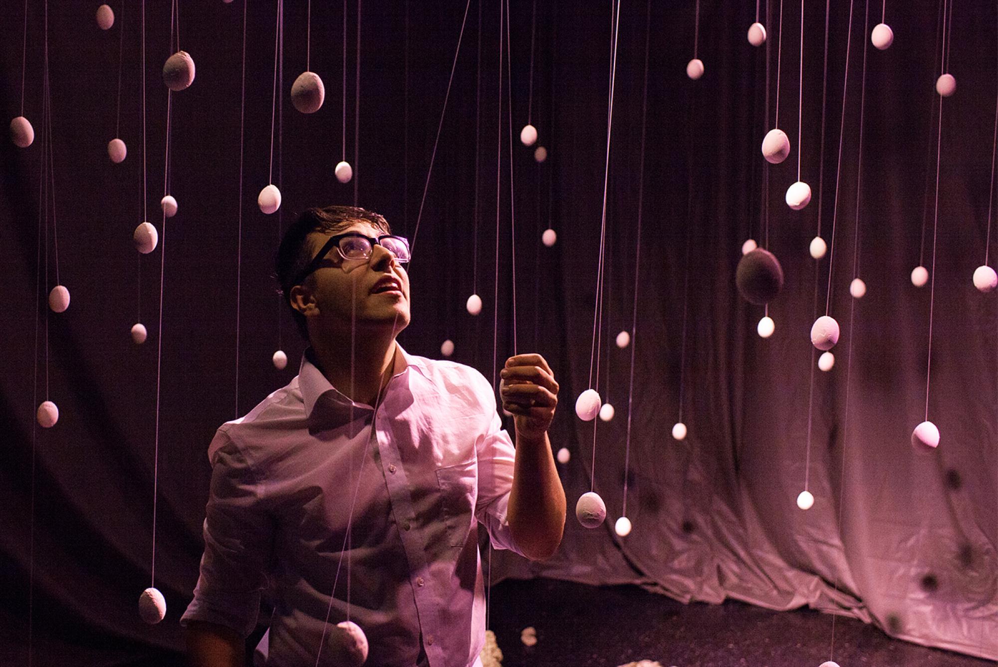 man in pink lighting touches a hanging prop