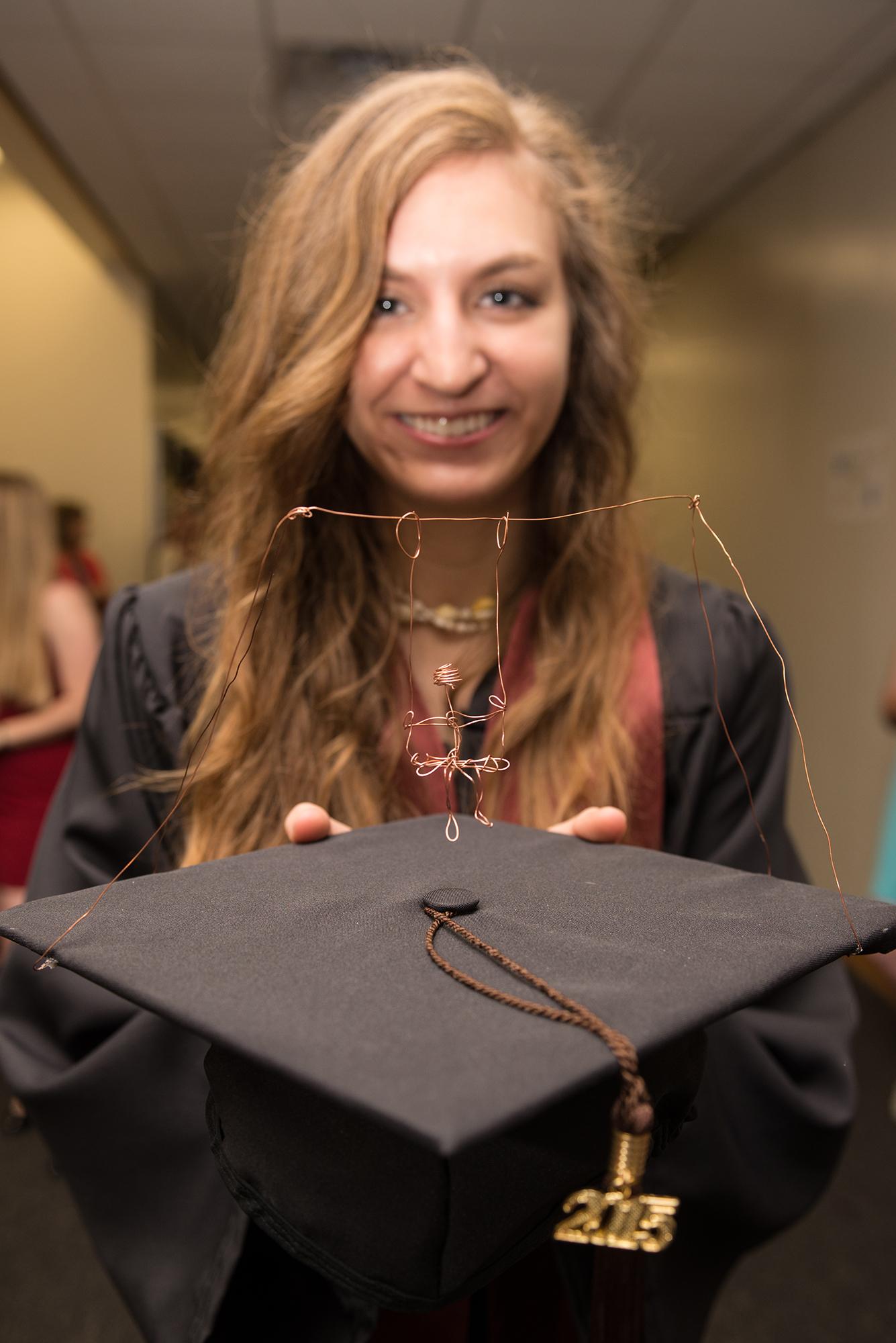 Woman showing her graduation cap which has a person swinging on top