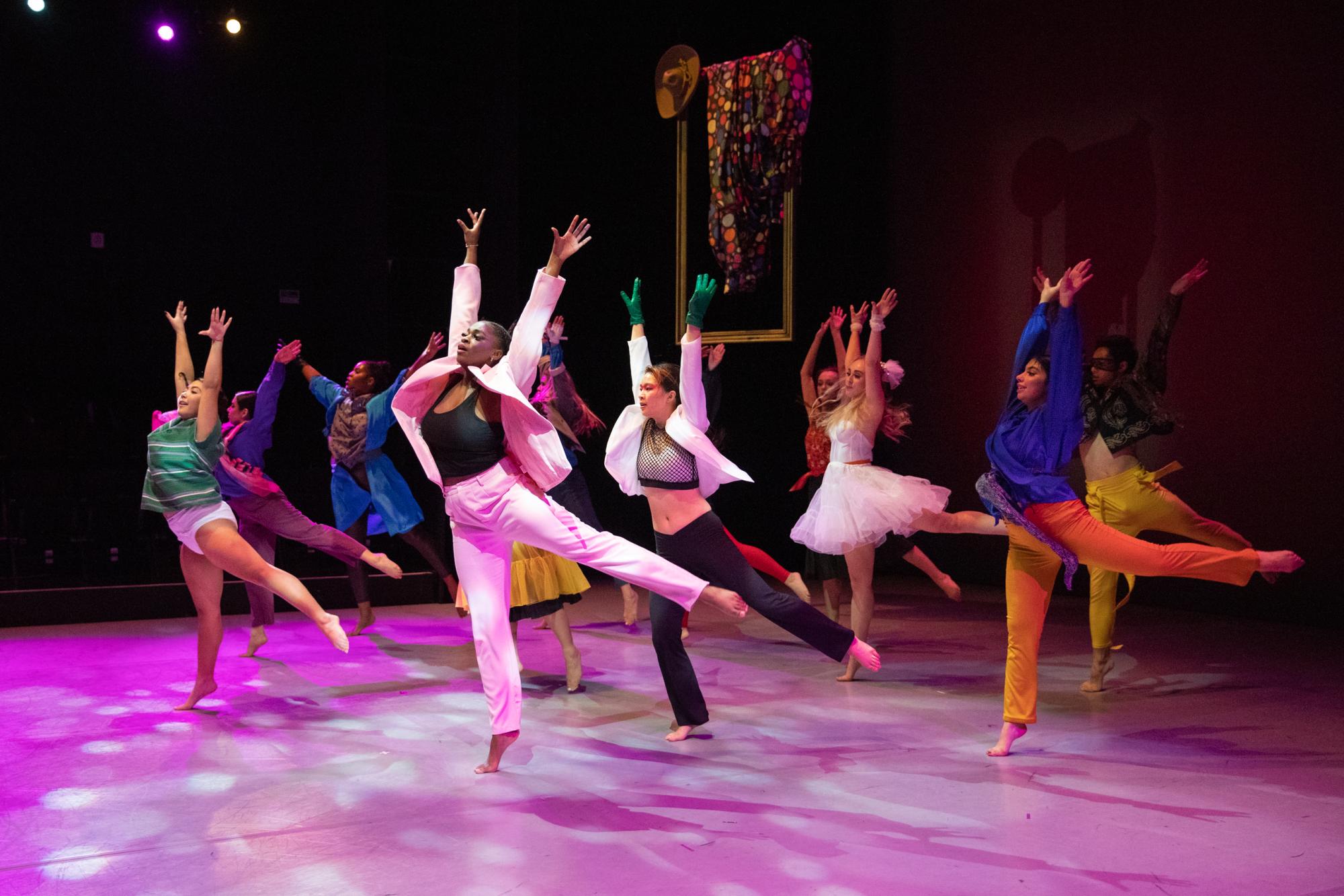 Dancers jump with their arms outstretched above their head