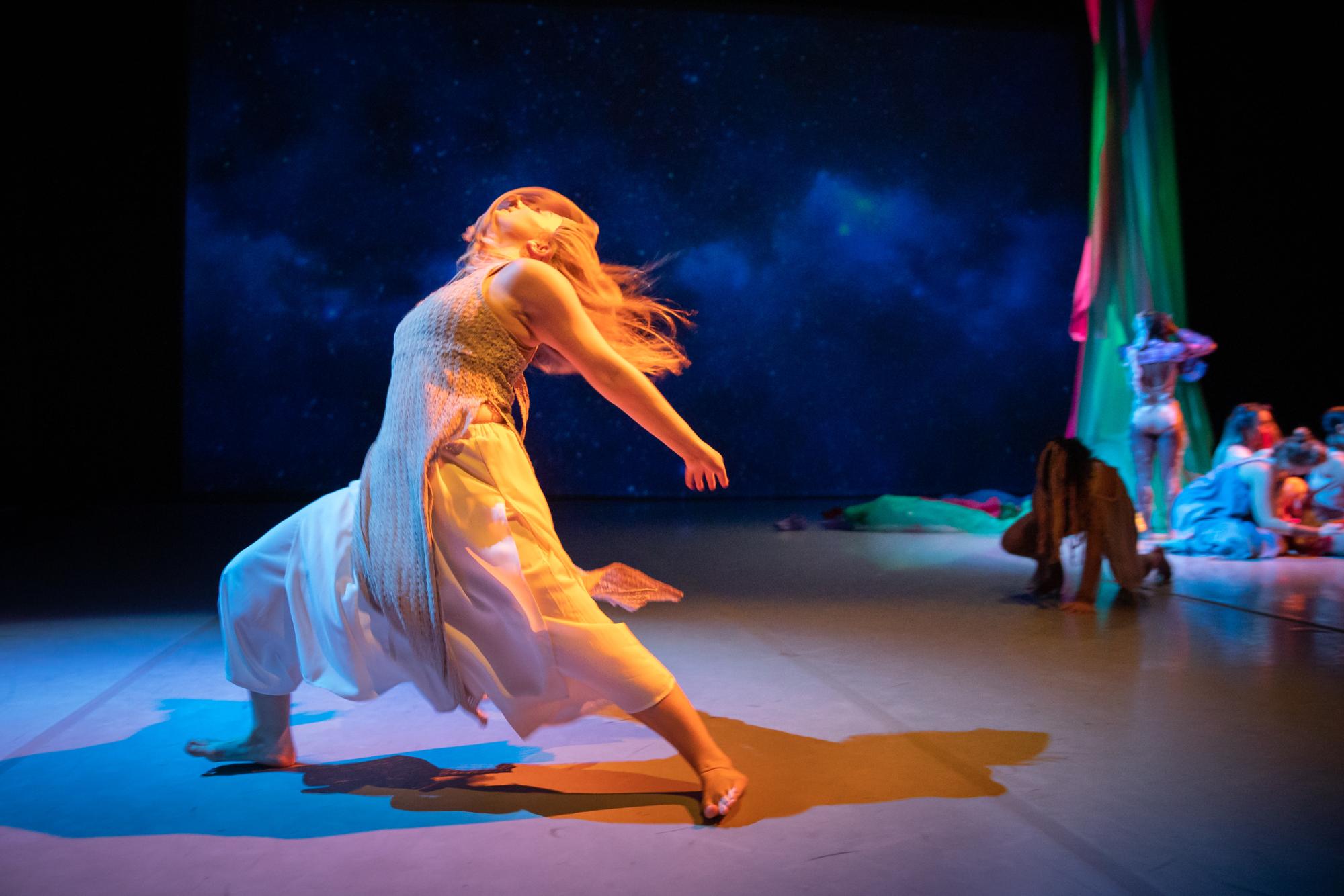 A dancer whose hair covers her face poses on stage