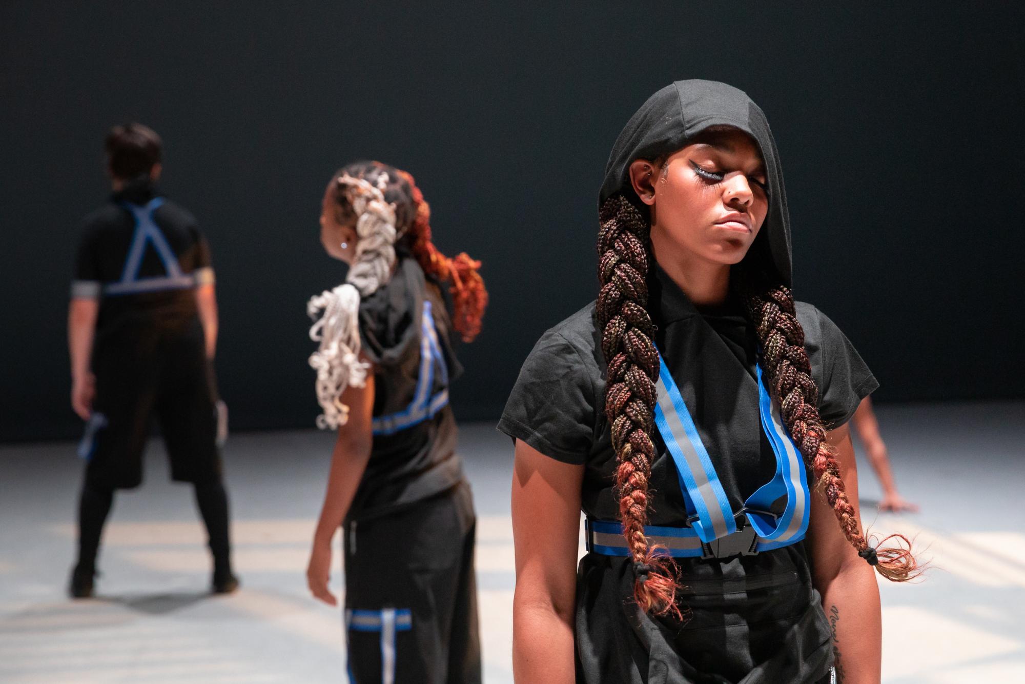 Dancers with high tech clothing stand on stage