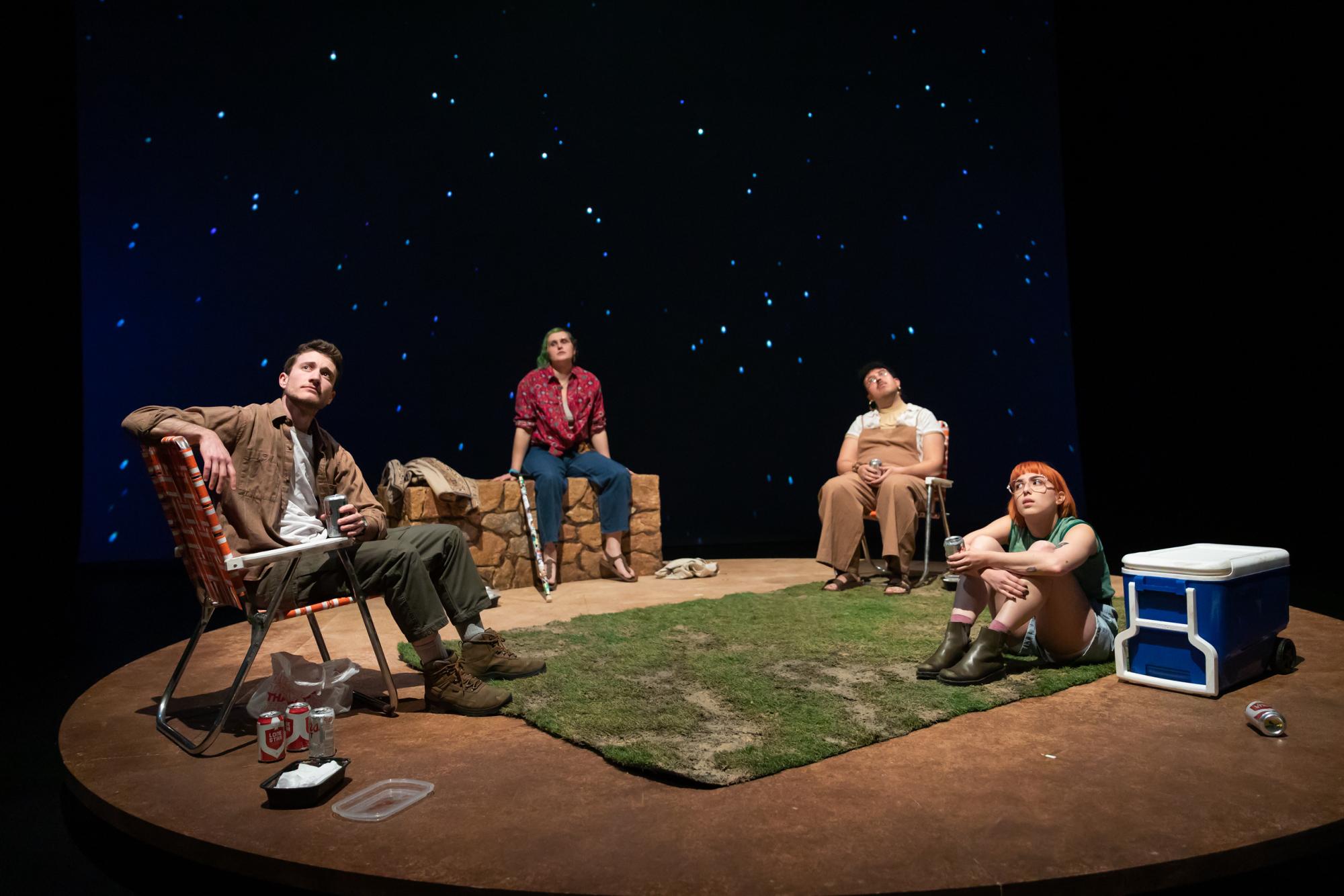 Four people camp in the desert, gazing at the stars