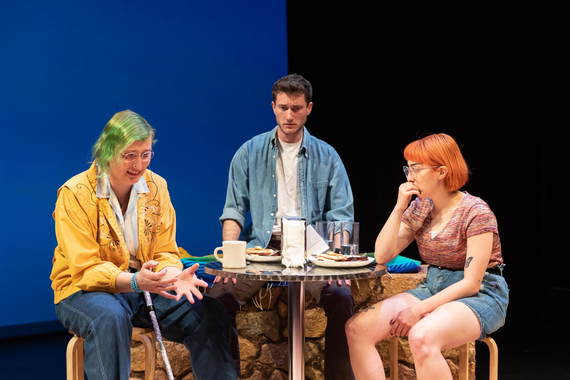 three people sit at a table, talking animatedly