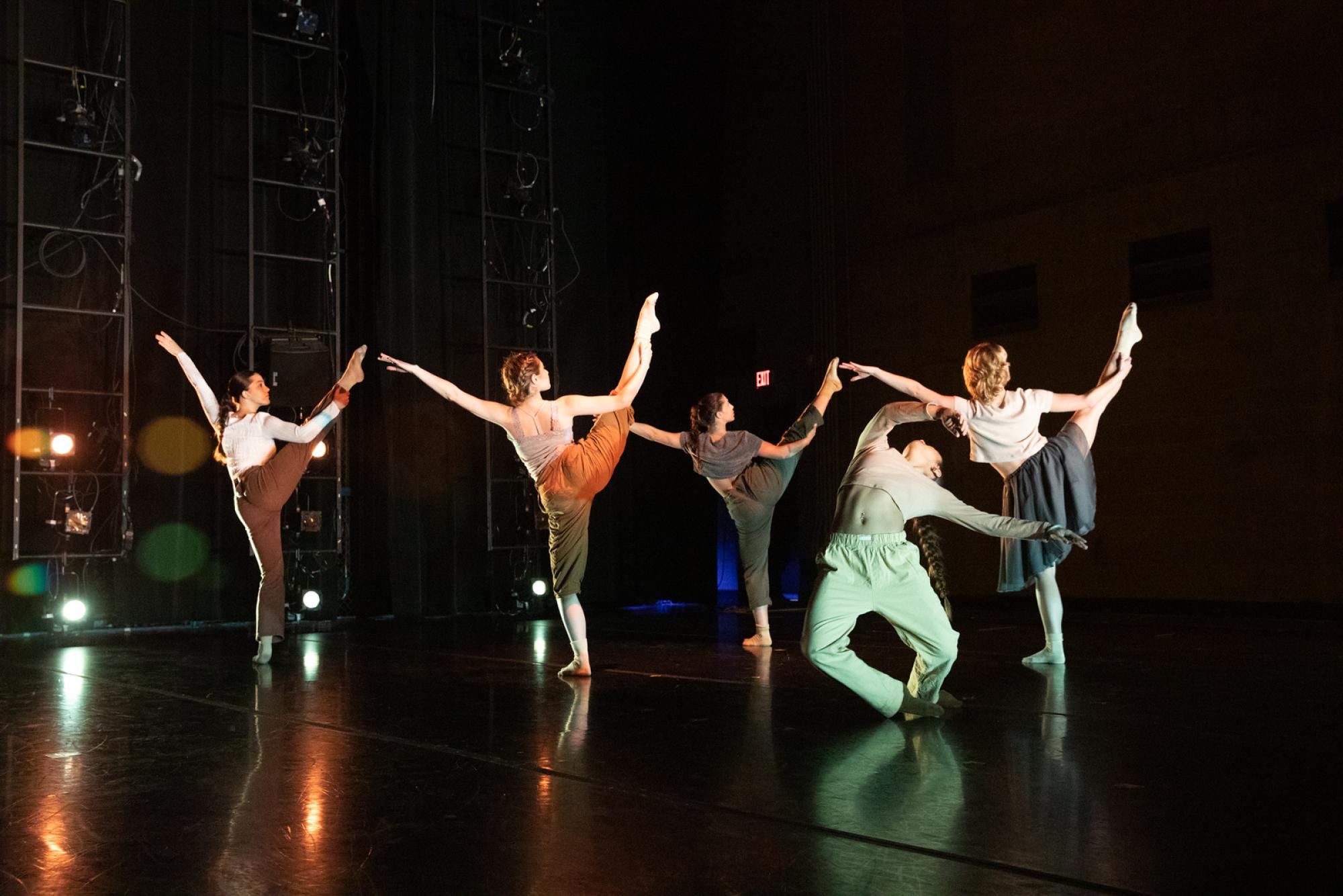 Dancers kick one leg up to the air as another falls over