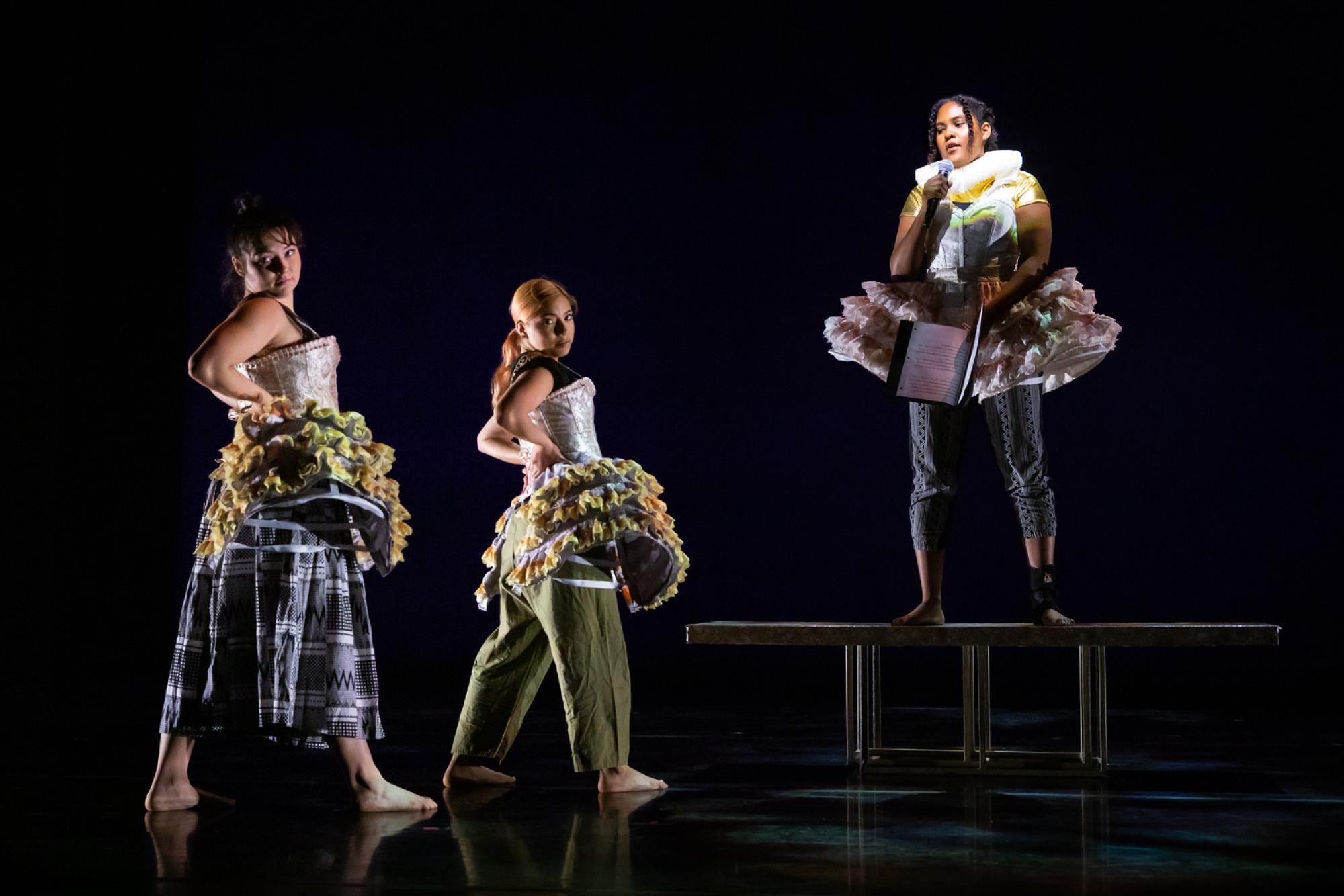 Three dancers in renaissance attire stand straight