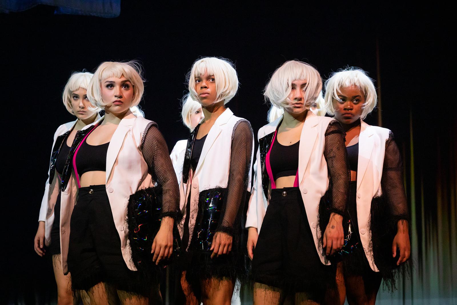 A group of white wigged dancers look serious