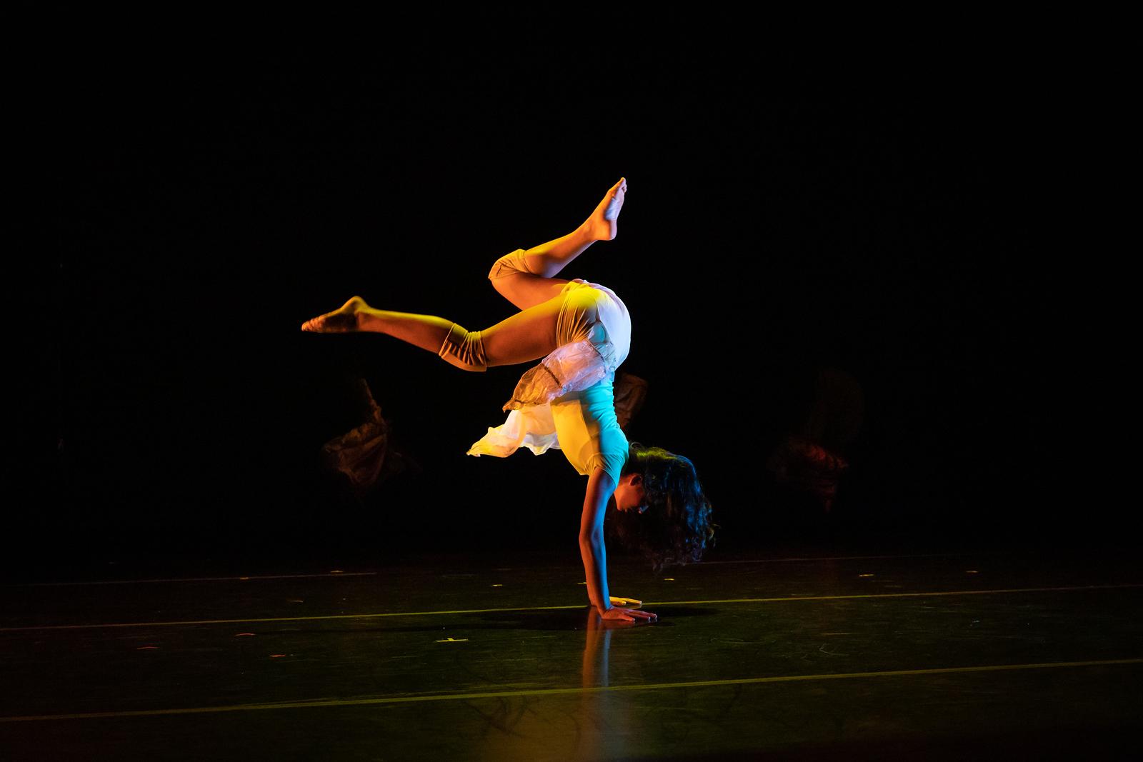 A dancer poses with their legs in the air