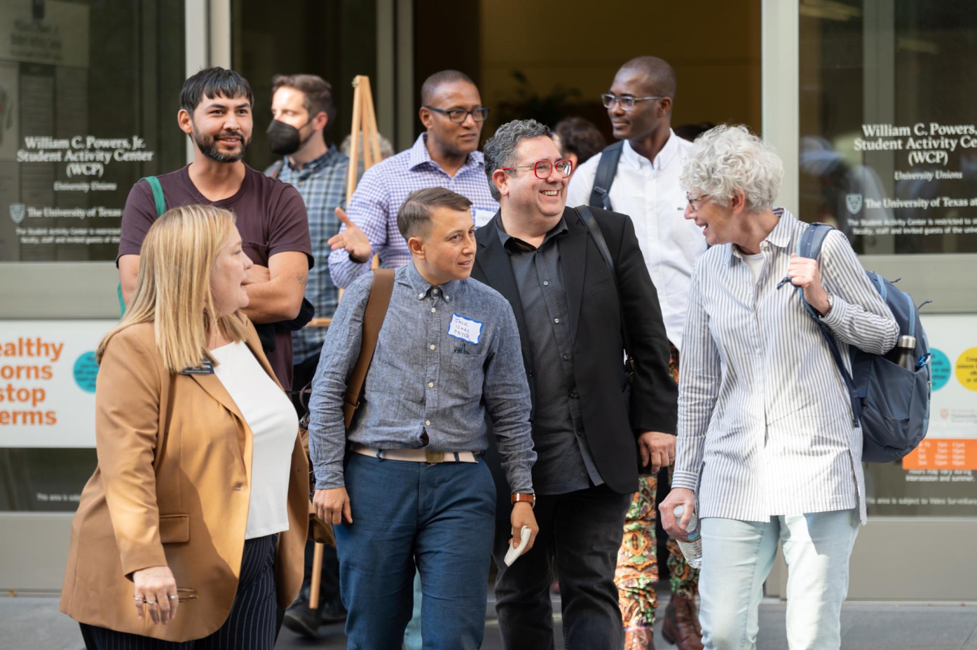 A group of faculty, former faculty, alumni and students attending the PPP@20 event walk outside through sliding class doors