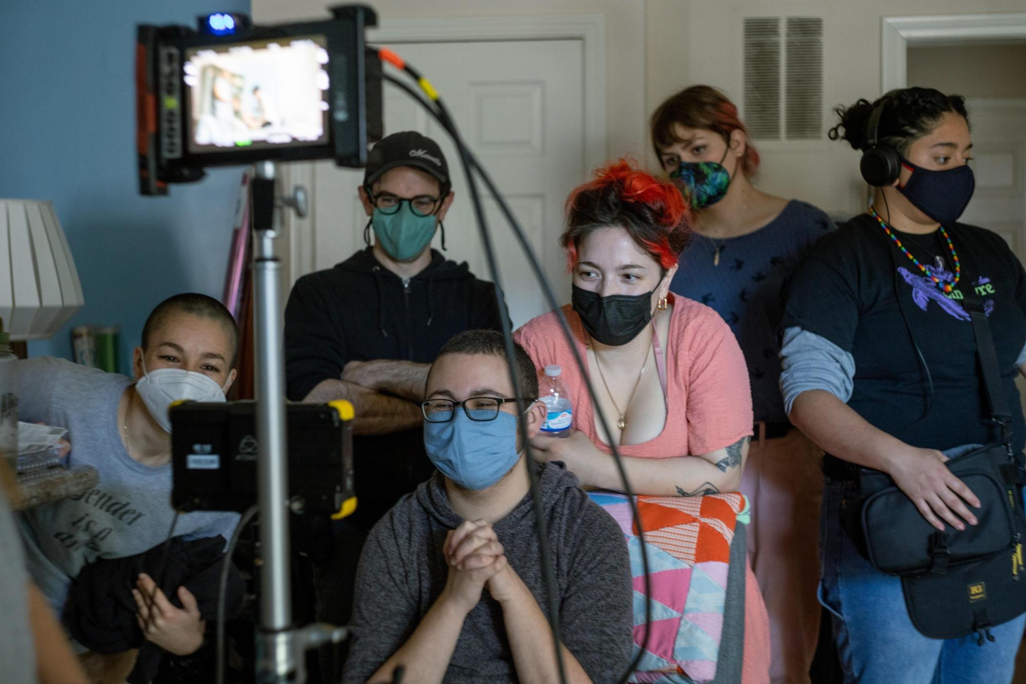 Filmmaker Lane Michael Stanley sitting with the production team for one of their films, looking joyfully at the camera screen