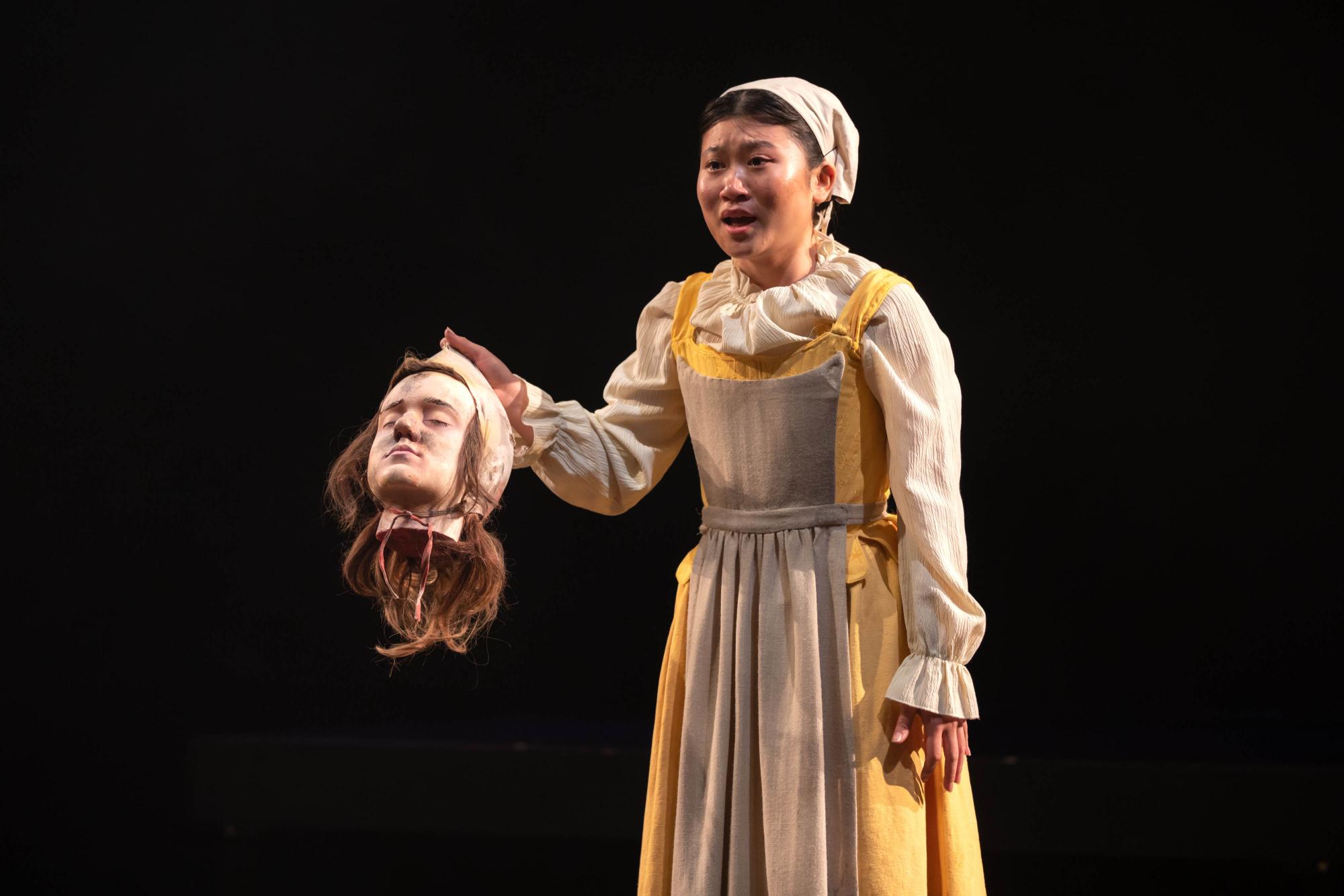 Mia Ngyuen as Sevallia stands holding the head of her son, Tybee.