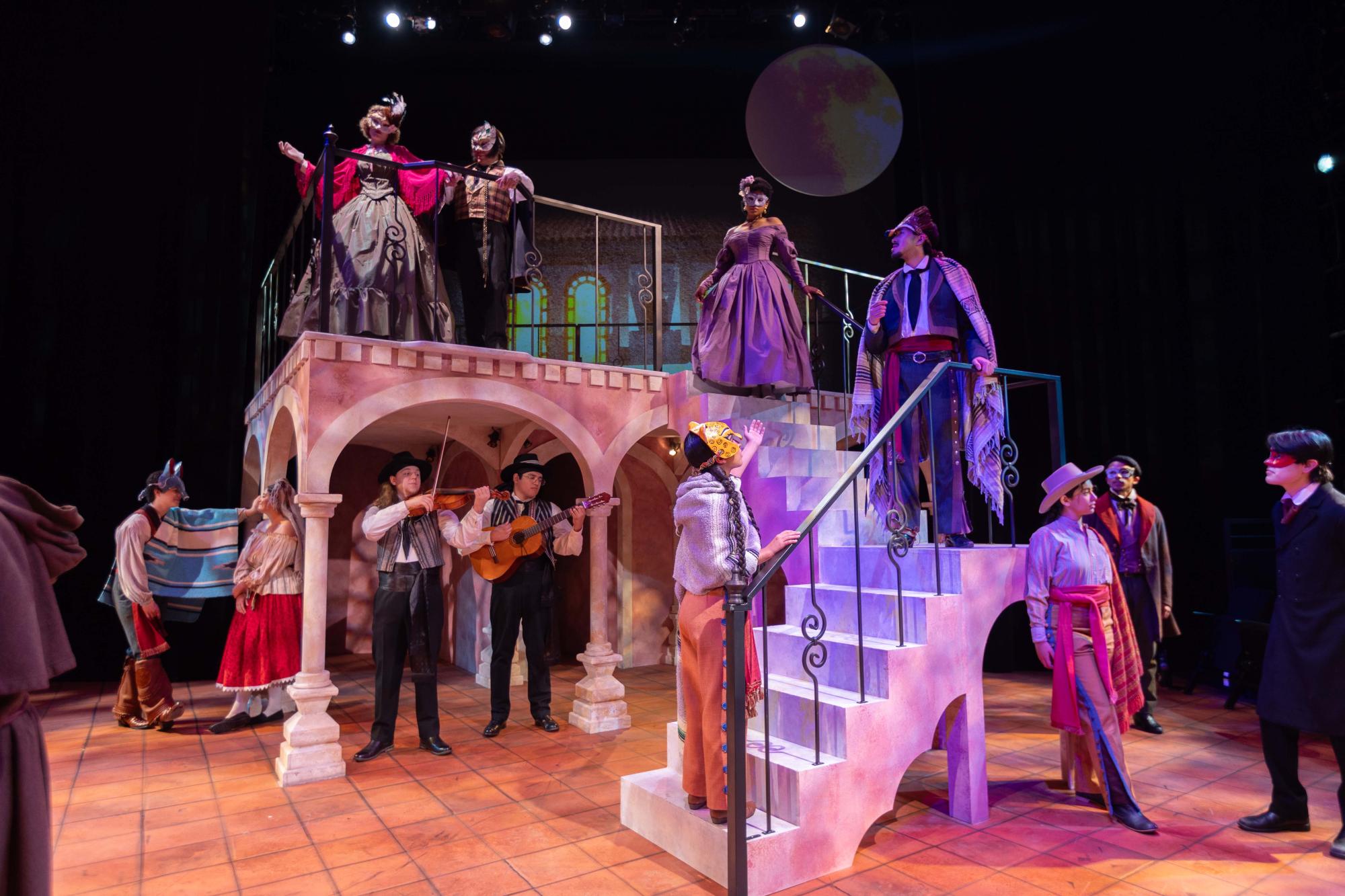 The cast of Romeo y Juliet stand scattered about the stage, in the midst of the famed masquerade party where Romeo first encounters her Juliet.