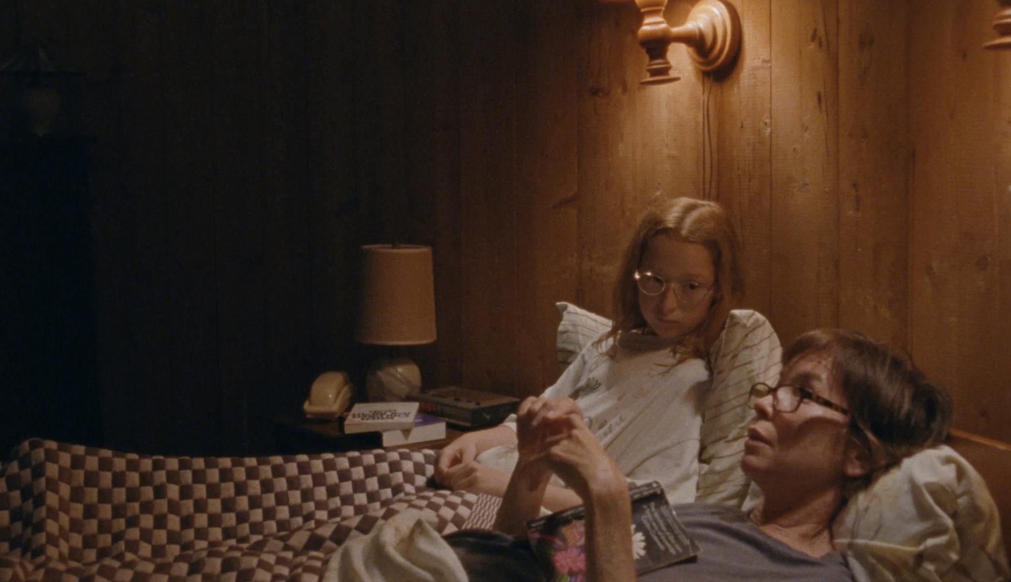 A scene from JANET PLANET in which a mother and daughter sit next to each other in a bed