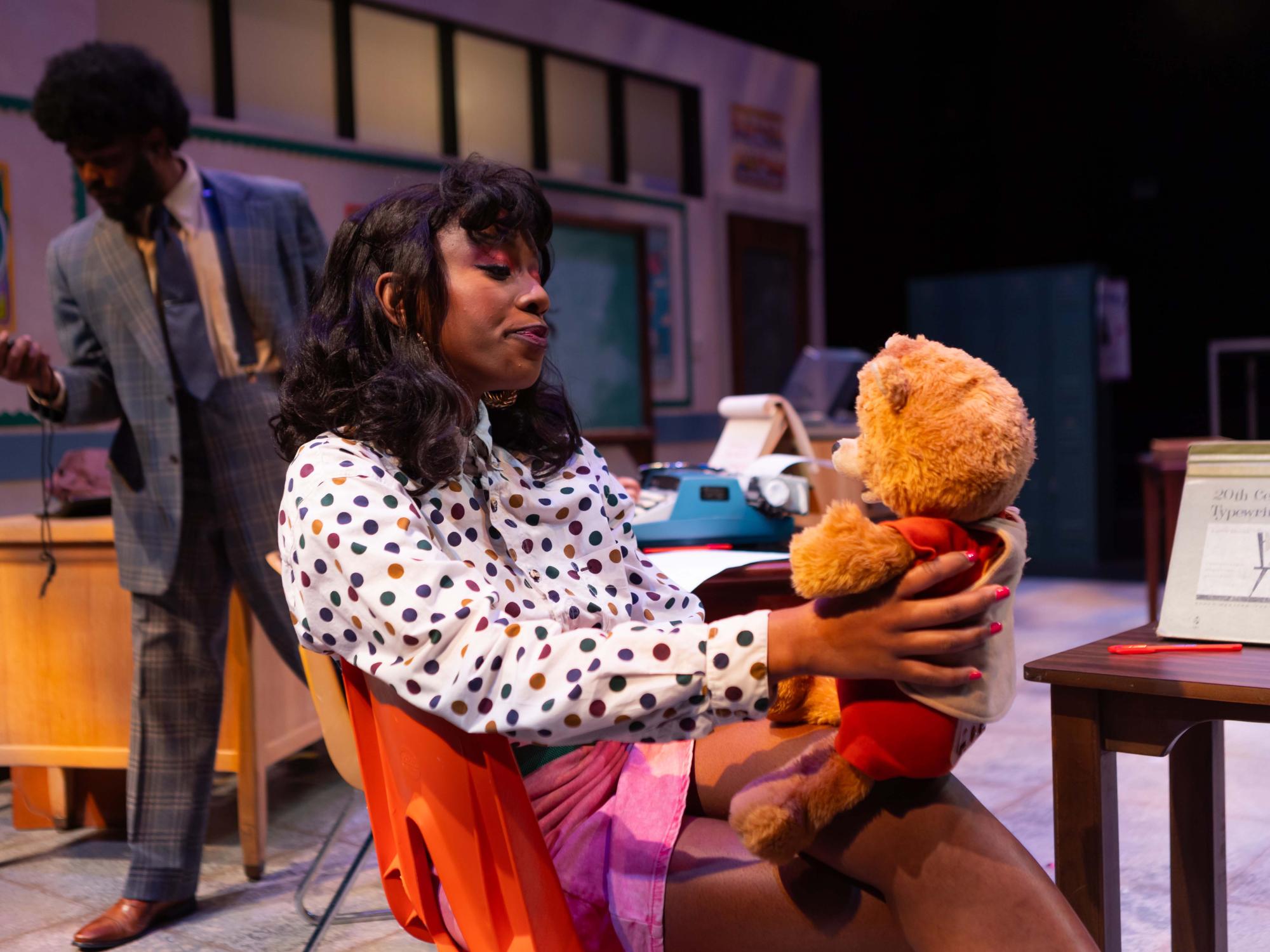 Tati's emotional support bear is held by Mahogany, Makayla Adelakun, while Tati, Heavyn Carter, completes a typing test.