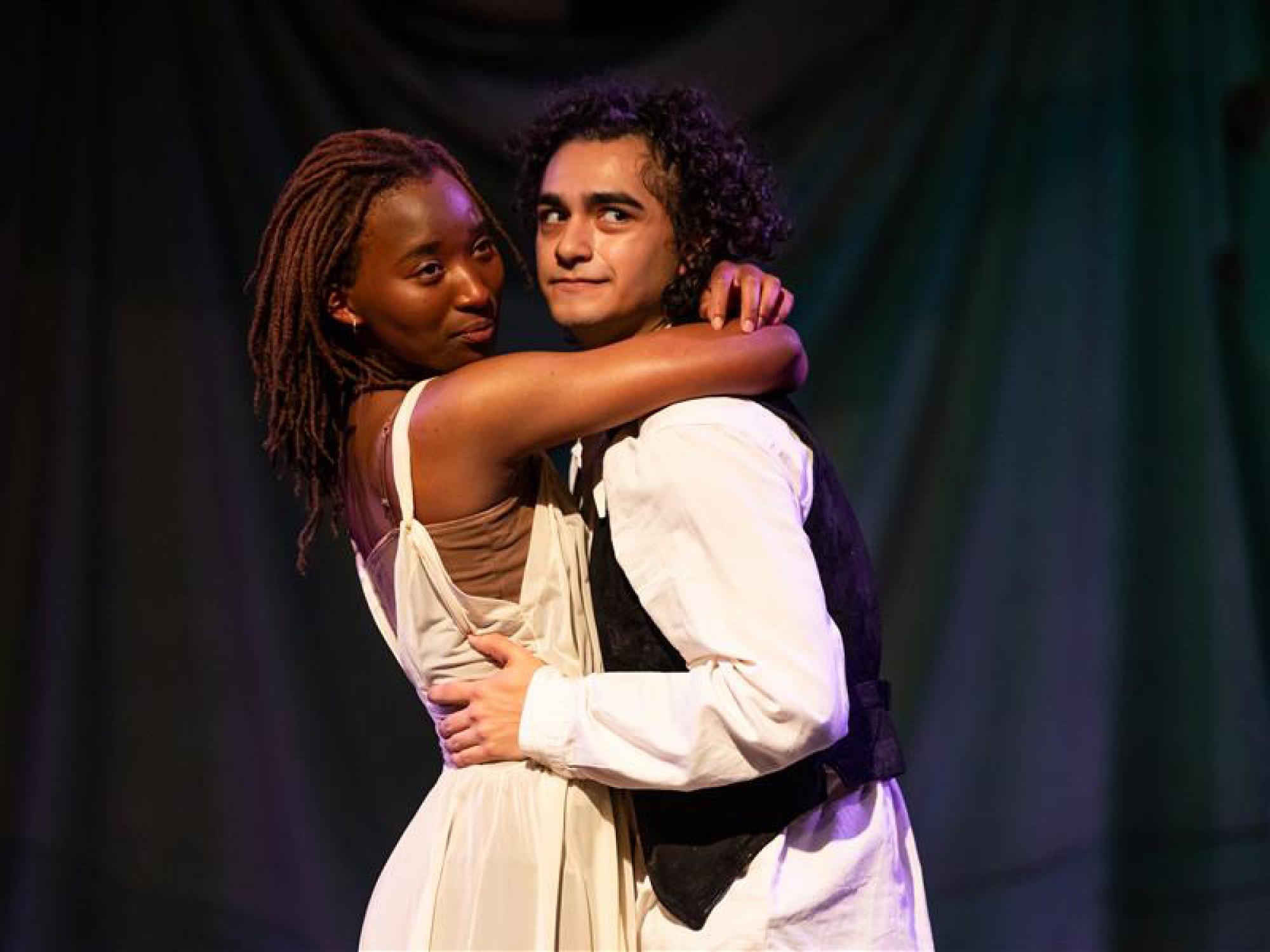 Eian Johnson as Nina stands in the arms of her lover Treplev, played by Adam Flores Jr., as they stare off-stage.