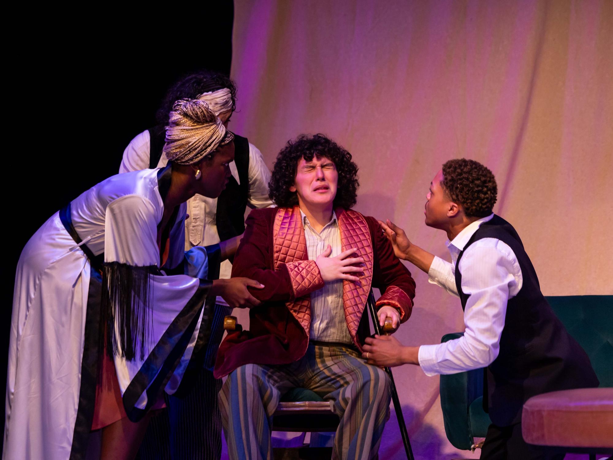 Always ill Uncle Sorin, played by Zoey Gonzales, coughs up a lung in a chair flanked by Medved, played by Isaiah Jones, Arkadina, portrayed by Oyin Ojomo, and Treplev, played by Adam Flores Jr.