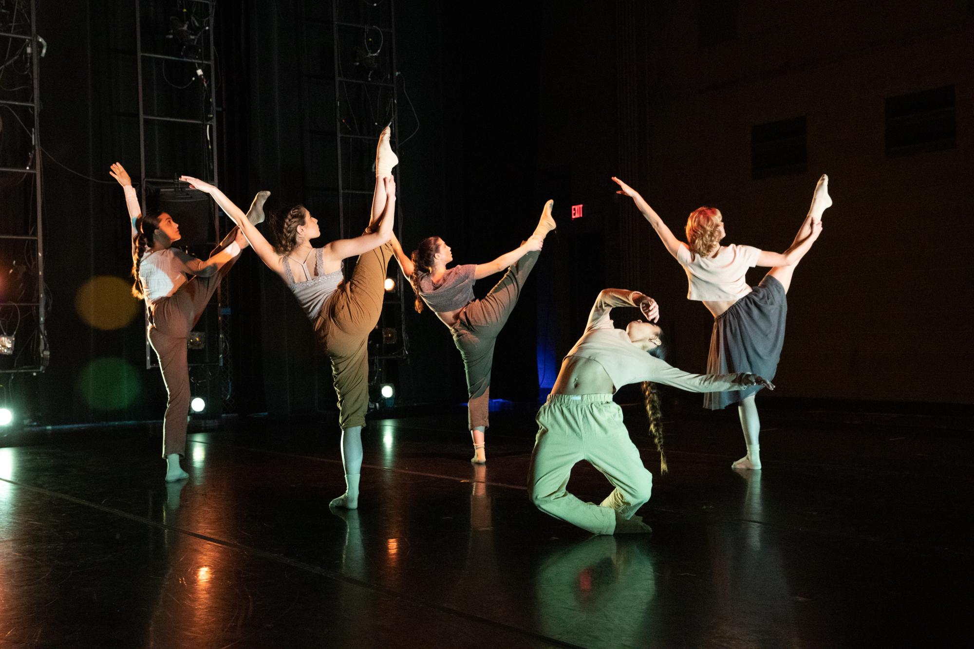 The dancers extend their legs upwards as one dancer falls to the ground geometrically