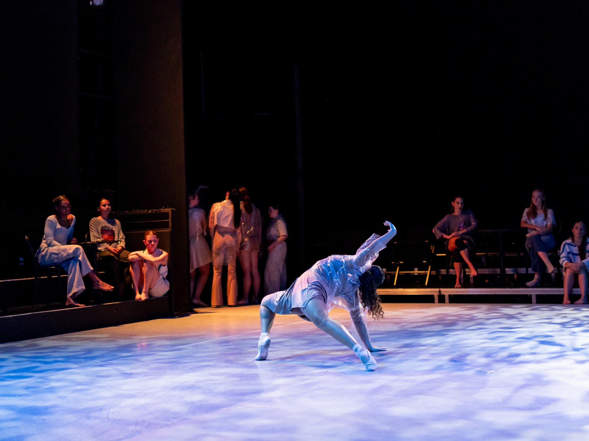A dancer exudes beauty and grace on the floor of the stage, twisting their body into a poetic position