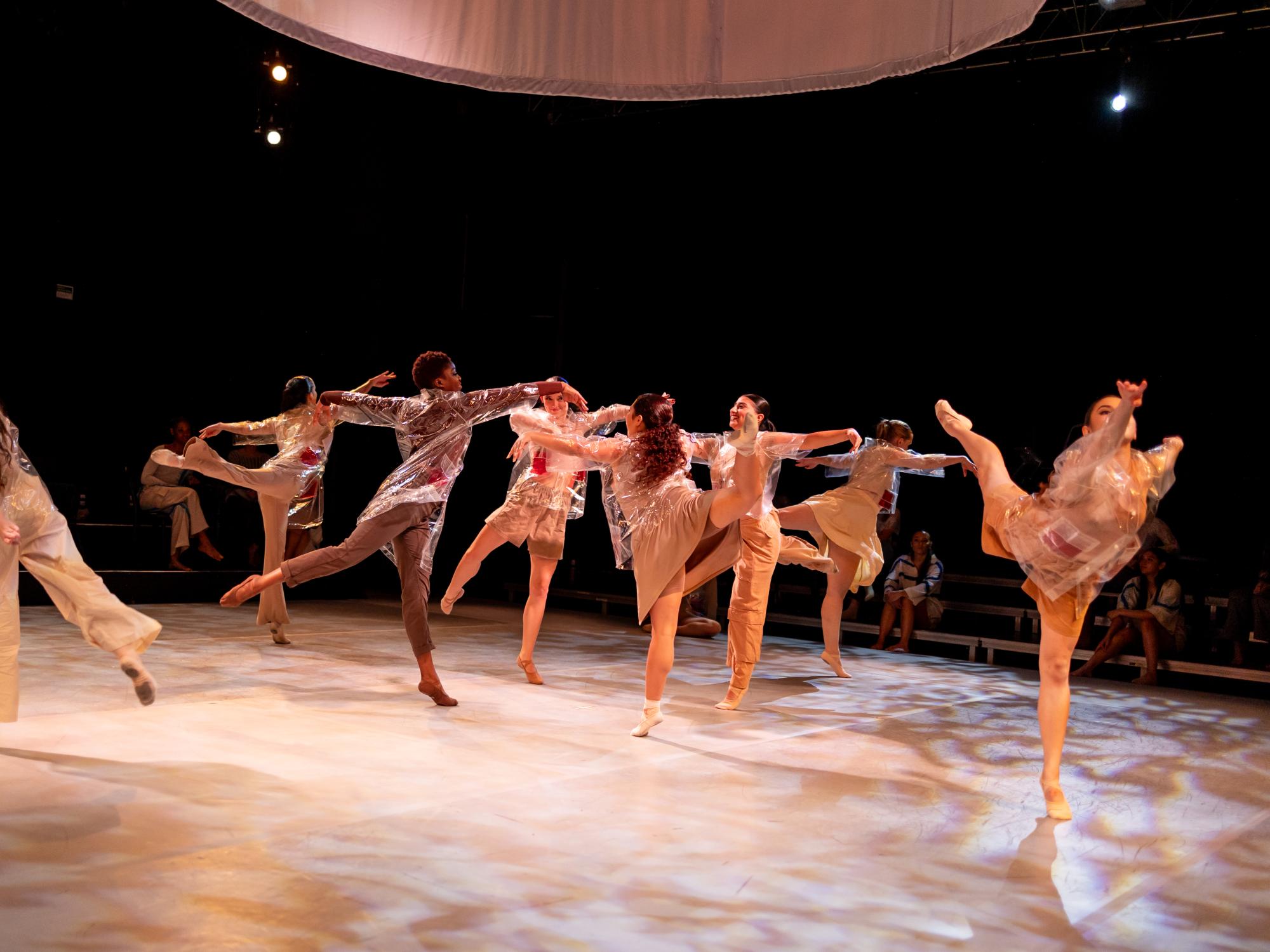 The dancers float across the stage with their legs extended behind them with their clear raincoats still on