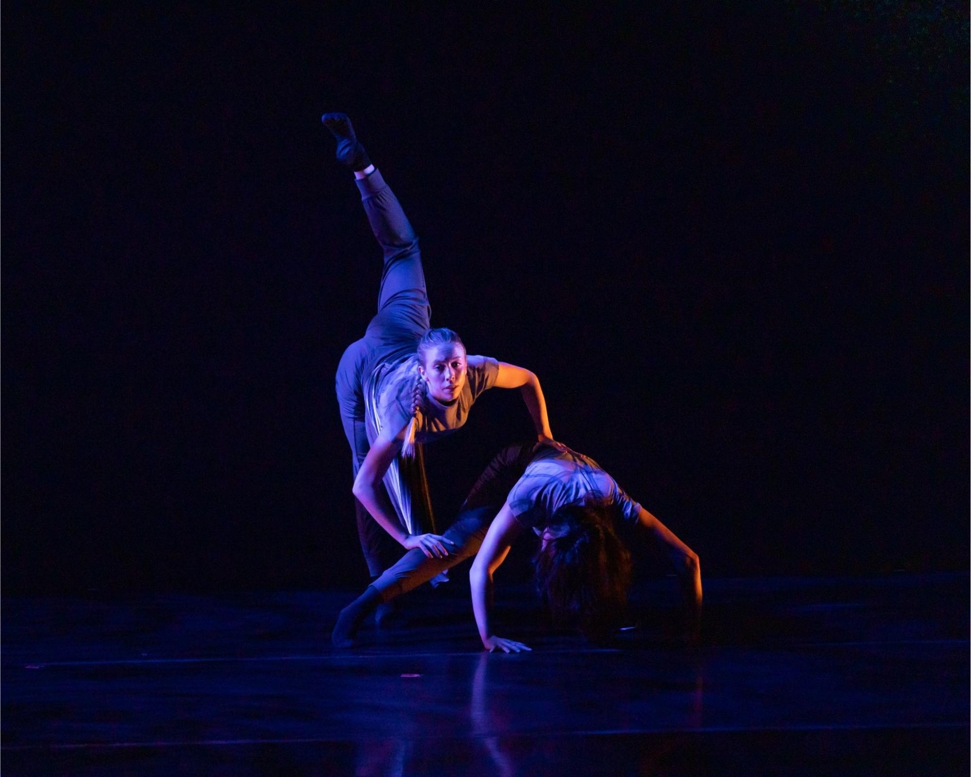 Photo of two dancers one low to the ground the other bend forward with leg stretched behind her
