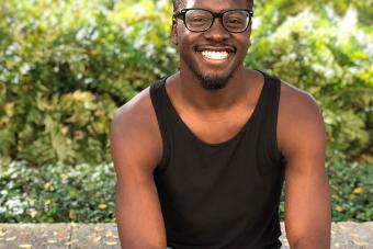 man in glasses sitting in front of a bush 