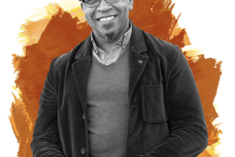 man in black and white with hat, glasses and layered clothing smiles, with orange brush strokes in the background