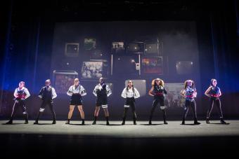eight dancers standing in a line on stage wearing black, white and red