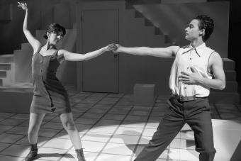 black and white photo of two people dancing, one wearing a dress and the other a button-up without sleeves