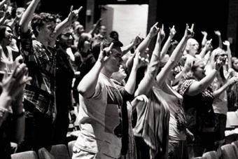 students making a hook em sign in a crowd.