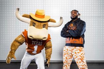 Person in Hook 'Em costume stands next to student Christian Coffey