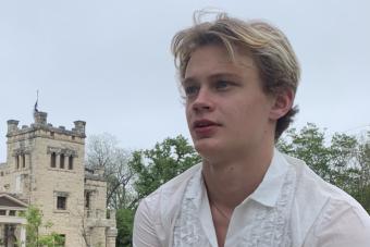 Oliver Aaro sitting in front of a large, castle-like building