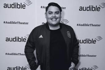 Isaac Gómez poses in front of an Audible banner