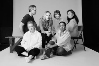 Five women in the cast of Annie Baker's INFINITE LIFE sit, looking directly at the camera, while a sixth cast member looks at them