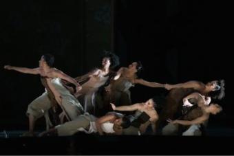 Seven dancers positioned as if they were holding onto each other