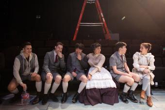 six actors in costumes for SPRING AWAKENING sit in the audience and talk between scenes