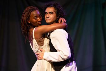 Eian Johnson as Nina stands in the arms of her lover Treplev, played by Adam Flores Jr., as they stare off-stage.