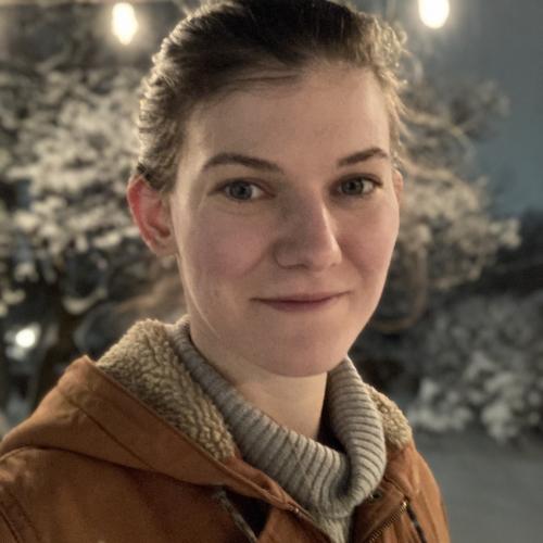 Photo of woman with brown hair pulled back, pale complexion and a brown coat