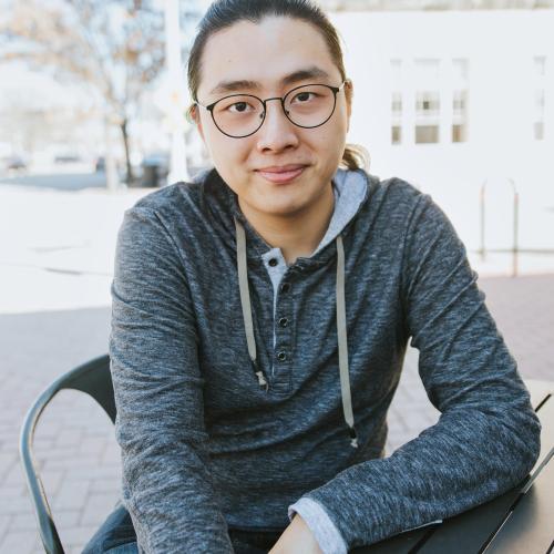 Asian man with glasses in grey hoodie