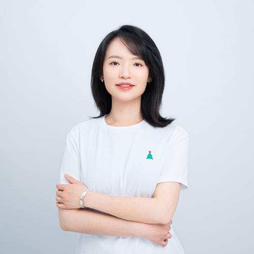 woman with shoulder length black hair and bangs standing in front of a white backdrop